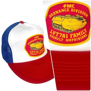 Può includere: Cappellino da camionista rosso, bianco e blu con retro in rete. Il pannello frontale è bianco e presenta una toppa con la scritta "FMC Ordnance Division LVT7A1 Family Assault Amphibians" e un'illustrazione di carro armato giallo.