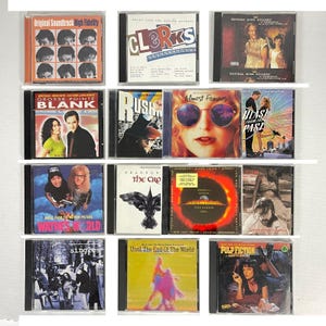 May include: A collection of various CD soundtracks and albums, including "High Fidelity," "Clerks," "Natural Born Killers," "Grosse Pointe Blank," "Rush," "Almost Famous," "Blast from the Past," "Wayne's World," "Singles," "The Crow," "Armageddon," "Until the End of the World," and "Pulp Fiction."