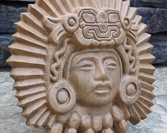 May include: A brown ceramic mask with a detailed face and headdress. The mask is decorated with intricate carvings and has a sunburst design around the edges.  Aztec Inca Ceremonial Mask 8" Aged Stone