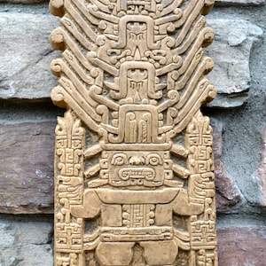 May include: A 14-inch aged stone stela from the Chavín culture of Peru. The stela features a carved figure with intricate designs and geometric patterns.