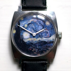 May include: A silver watch with a black leather band. The watch face features a printed image of Vincent van Gogh's "Starry Night" painting.