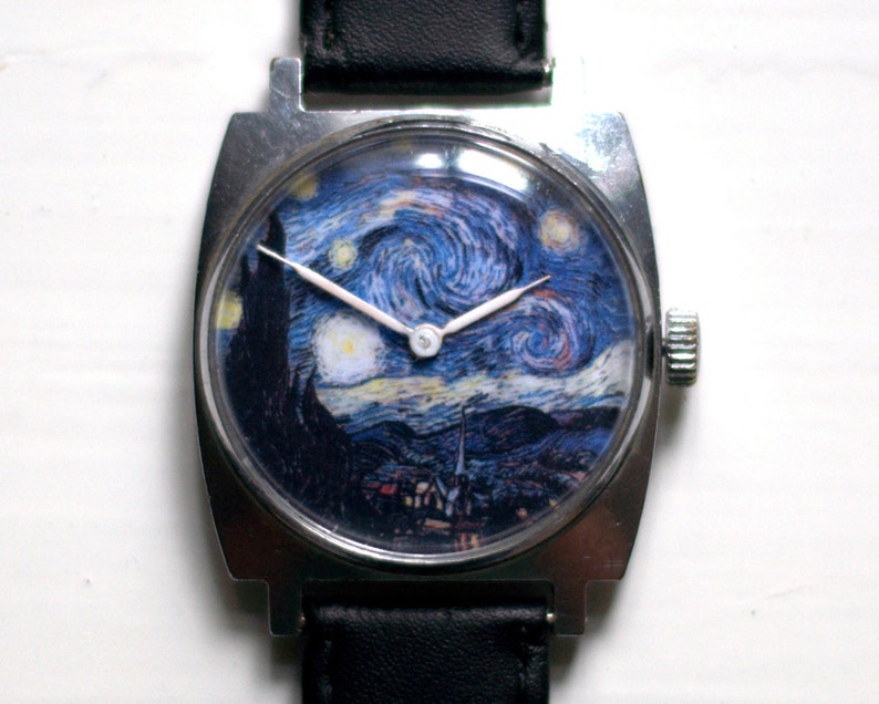 May include: A silver watch with a black leather band. The watch face features a printed image of Vincent van Gogh's "Starry Night" painting.