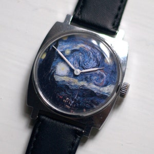 May include: A silver wristwatch with a black leather band. The watch face features a reproduction of Vincent van Gogh's "Starry Night" painting.