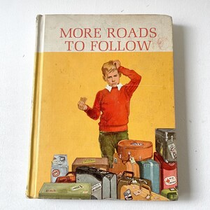 May include: A vintage children's book cover with the title "More Roads To Follow". The cover features a young boy in a red sweater and green pants standing in front of a pile of luggage with various destination stickers. The background is a yellow color.