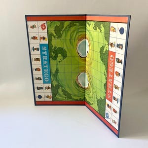 May include: A vintage board game with a green and blue map of the world. The game is called "Stratego" and is folded open to show the game board.