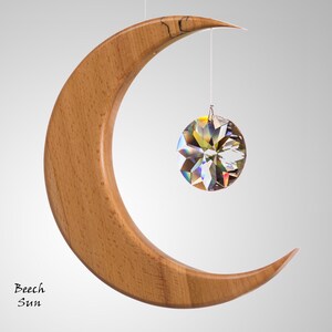 May include: A wooden crescent moon mobile with a faceted crystal sphere suspended beneath. The moon is made of light brown wood. The crystal reflects multiple colours. The text "Beech Sun" is in the lower left corner.