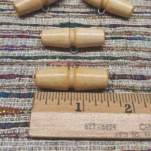 May include: Five wooden toggle buttons with metal loops. The buttons are approximately 1 inch long. A ruler is in the background.