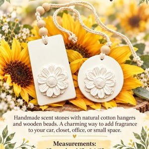 May include: Two white ceramic scent stones, one rectangular and one circular, each featuring a raised daisy relief. They include natural cotton cords with wooden beads. Text reads: Scent Stone Defuser, Measurements: 2" round and 2" x 3-1/2".