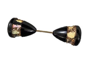 Puede incluir: Un broche vintage negro y dorado con un alfiler. El broche está hecho de dos piezas en forma de lágrima con un alfiler dorado que las conecta.
