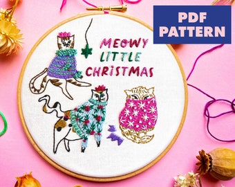 May include: Embroidered hoop art featuring three cats wearing festive sweaters. The cats are surrounded by the text "MEOWY LITTLE CHRISTMAS".