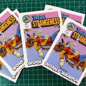 May include: A stack of comic books titled "Mid Strangeness" featuring a cartoon dog character. The cover art includes the text "Jackdaw Comics No. 1 Spring 2026" and "Introducing Wonky Wampus". The comics have a pink and blue color scheme.