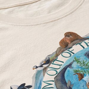 a close-up view of a white t-shirt with a colorful graphic design depicting various animals, including a walrus, penguins, and other marine creatures.