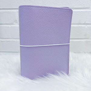 May include: A lavender-colored leather-bound journal with a white elastic band closure.