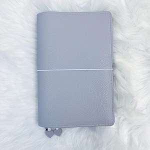 May include: A light gray leather planner with a white elastic closure and two silver heart-shaped charms.