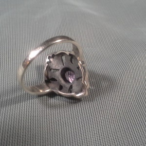 May include: A silver ring with a purple gemstone set in a detailed design.