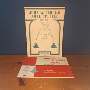 May include: Two vintage music books, one titled "John W. Schaum Note Speller Book One" with a green and brown cover and the other titled "Belwin Pre-Instrument Method by Fred Weser" with a red and white cover.