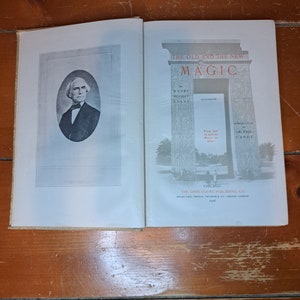 Może przedstawiać: Antyczna książka zatytułowana "The Old and the New Magic" autorstwa Henry'ego Ridgely'ego Evansa, zilustrowana przez dr. Paula Carusa. Okładka książki przedstawia czarno-białe zdjęcie Roberta Houdina, słynnego iluzjonisty.