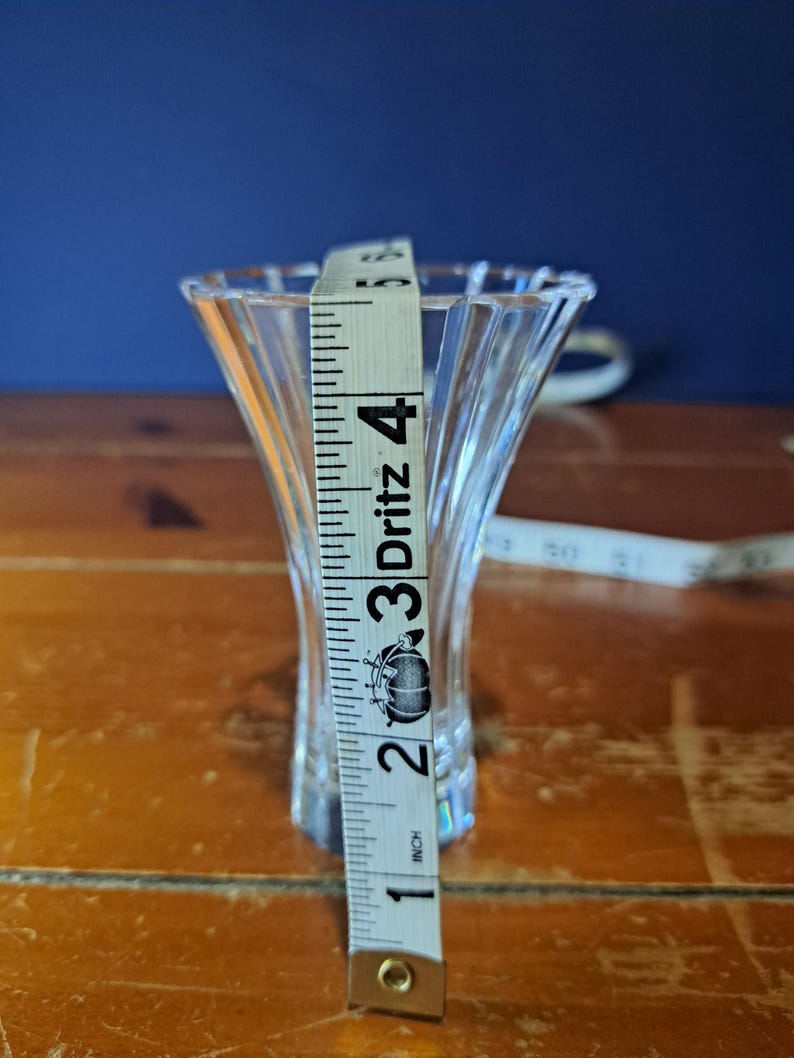 Puede incluir: Un jarr&oacute;n de vidrio transparente y acanalado con la parte superior acampanada. Una cinta m&eacute;trica muestra que el jarr&oacute;n mide aproximadamente 10 cm de alto. El jarr&oacute;n est&aacute; sobre una superficie de madera con un fondo azul oscuro.
