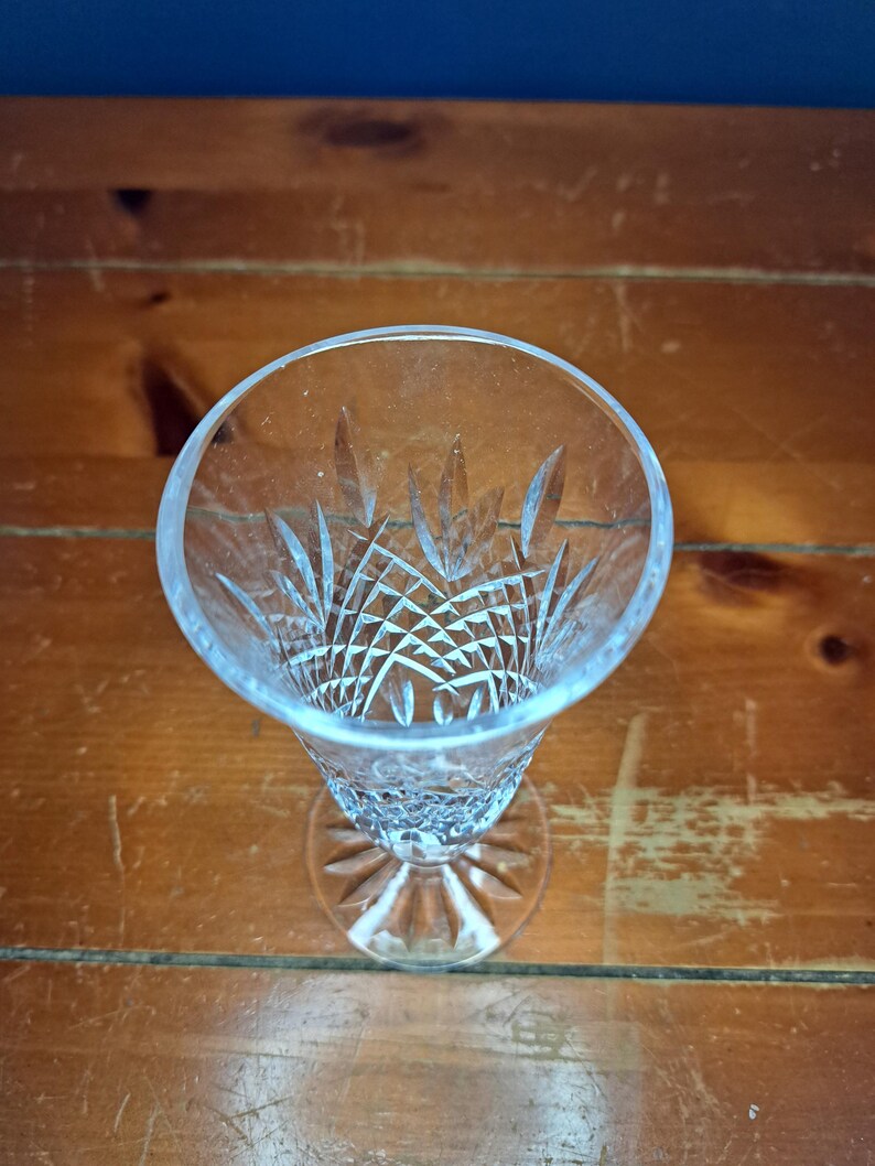 Puede incluir: Una copa de champ&aacute;n transparente, tallada en cristal, con un patr&oacute;n detallado en el cuenco y una base redonda. El vaso est&aacute; colocado sobre una superficie de madera, mostrando su intrincado dise&ntilde;o y forma elegante. El vaso mide unos 18 cm de alto.