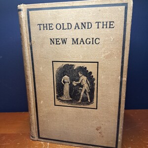 Może przedstawiać: Antyczna książka z beżową okładką i czarnym tekstem, kt&oacute;ry brzmi "The Old and The New Magic". Okładka zawiera czarno-białą ilustrację mężczyzny i kobiety w strojach z epoki.