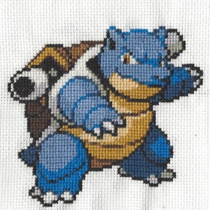 May include: A blue and brown cross-stitch of a Pokemon character, Blastoise, with a shell on its back.