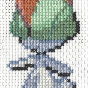 May include: Cross-stitch design of a stylized creature with a blue body, green head, and orange accents. The handmade embroidery is on white fabric, showcasing the detailed stitches and color palette.