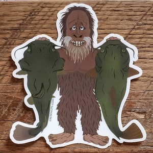 May include: A sticker featuring a cartoon illustration of a brown, hairy creature holding two green catfish. The creature has a long beard and a surprised expression. The sticker has the text "creeknuts.com" on the bottom left corner.