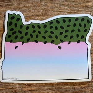 May include: A sticker of the state of Oregon shaped like a trout with green, pink, and blue colors. The sticker has the text "CREEKNUTS.COM" at the bottom.