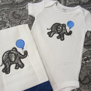 May include: A white baby onesie and a white burp cloth with a blue and gray paisley elephant holding a blue balloon embroidered on each. The onesie has the text "Carter's" on the tag.