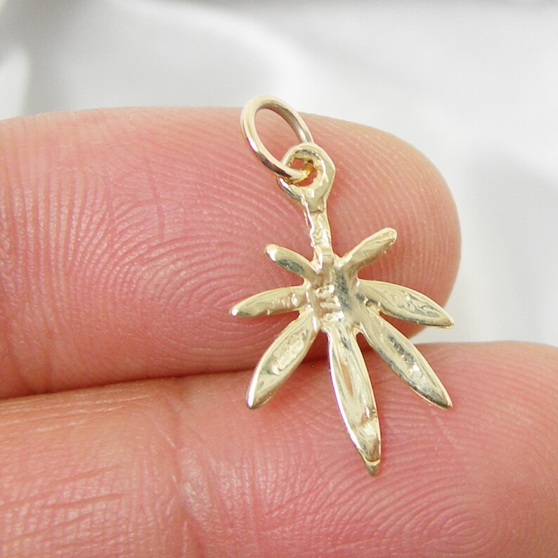 May include: Gold-toned marijuana leaf charm pendant. The charm is detailed with a realistic leaf design and has a loop at the top for attaching to a necklace or bracelet.