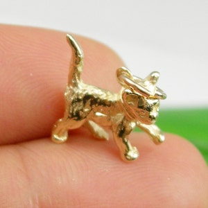 K&ouml;nnte beinhalten: Ein goldener Anh&auml;nger in Form eines laufenden K&auml;tzchens. Der Anh&auml;nger hat oben eine Schlaufe zum Anbringen an einer Halskette oder einem Armband.