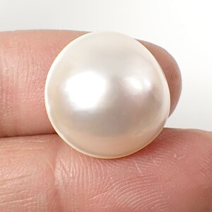 May include: A large, round, white pearl with a smooth, glossy surface.