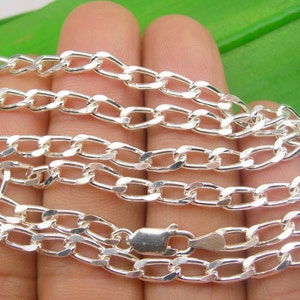 May include: A silver chain necklace with a curb link design. The chain is made of polished silver and has a smooth, shiny finish.