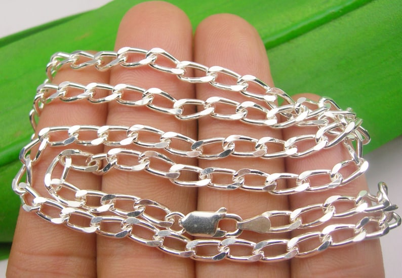 May include: A silver chain necklace with a curb link design. The chain is made of polished silver and has a smooth, shiny finish.