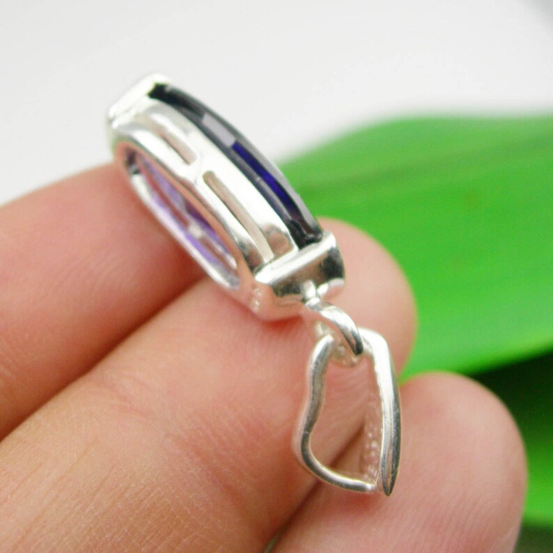 May include: A silver pendant with a heart-shaped bail and a rectangular purple gemstone set in a silver frame.