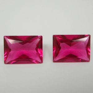 Könnte beinhalten: Zwei leuchtend rosa rechteckige Edelsteine mit Facettenschliff.