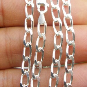 May include: A silver curb chain necklace with a lobster clasp. The chain is made of interlocking oval links.