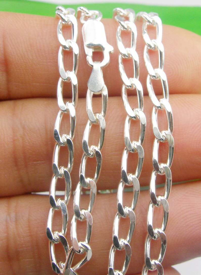 May include: A silver curb chain necklace with a lobster clasp. The chain is made of interlocking oval links.