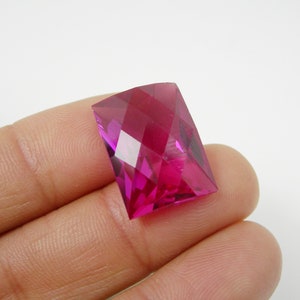 May include: A faceted, rectangular, pink gemstone with a high polish.