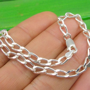May include: A silver chain bracelet with a lobster clasp closure. The chain is made of a double row of oval links.
