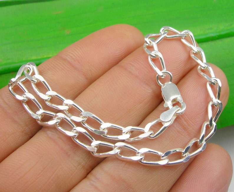 May include: A silver chain bracelet with a lobster clasp closure. The chain is made of a double row of oval links.