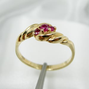 May include: A gold ring with three ruby stones set in a twisted band.