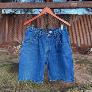 May include: A pair of blue denim shorts with a classic five-pocket design. The shorts have a relaxed fit and a straight leg.