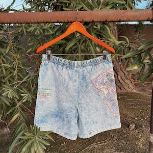 May include: Light blue denim shorts with a map print on the back pocket. The shorts have a drawstring waist and are made of a soft, comfortable fabric.