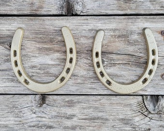May include: Two gold-colored horseshoes on a weathered wooden background.