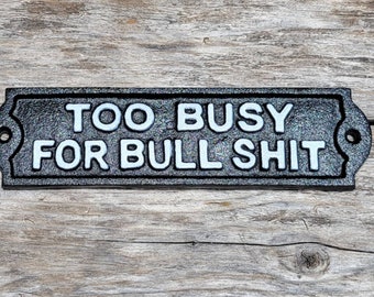 May include: Black metal sign with white lettering that reads "Too Busy For Bull Shit".