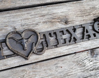 May include: Black metal sign with the words "I Love Texas" and a heart-shaped design featuring a longhorn steer head.