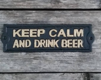 May include: Black cast iron sign with gold lettering that reads "Keep Calm and Drink Beer".