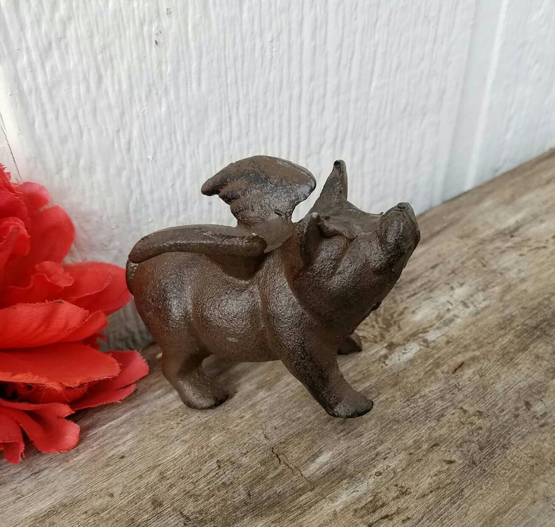 K&ouml;nnte beinhalten: Eine Schweinefigur aus Gusseisen mit Fl&uuml;geln. Das Schwein ist braun und hat ein detailliertes Gesicht. Die Fl&uuml;gel sind ausgebreitet und ebenfalls aus Gusseisen.