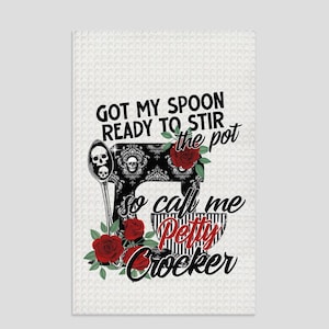 Peut inclure: Une serviette de cuisine blanche avec une illustration noir et blanc d'un batteur sur socle avec des roses rouges et des crânes. Le texte dit "Got my spoon ready to stir the pot so call me Petty Crocker."